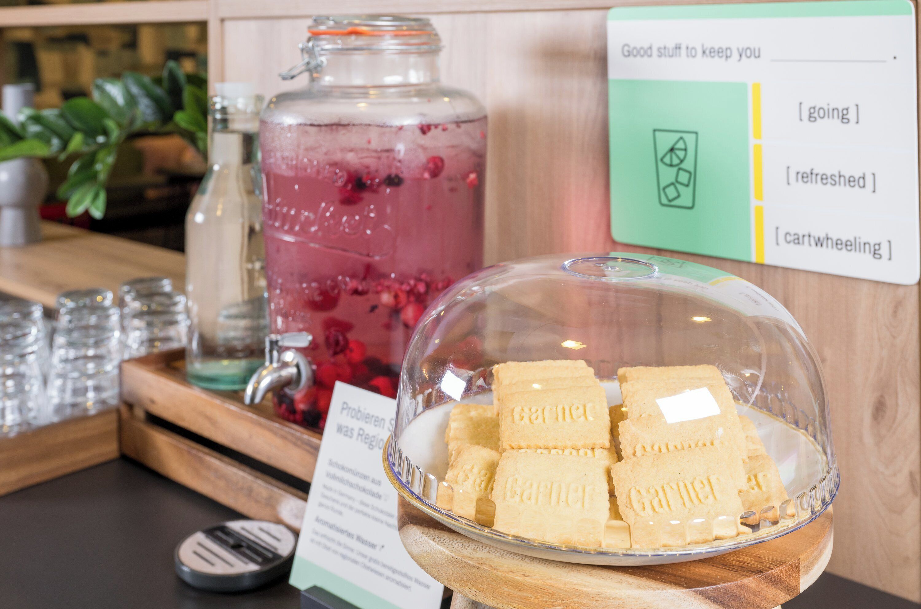 A glass jar filled with a pink beverage, a bowl of cookies, and a sign with text.
