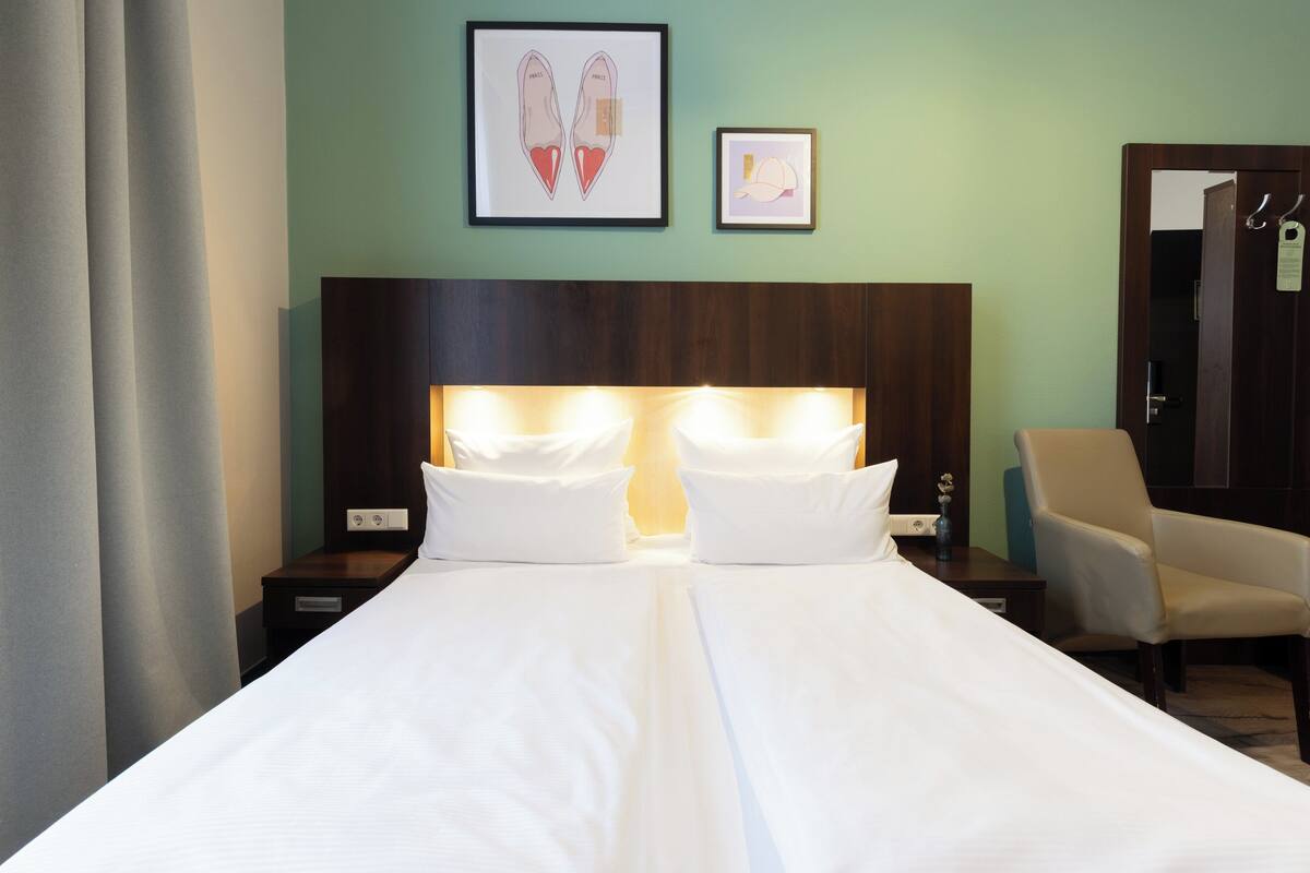 A hotel room with a large bed, two bedside tables, a chair, and artwork on the wall.