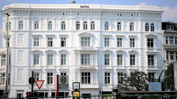 Un edifici de color blanc amb el rètol “HOTEL”, nombroses finestres i un estil arquitectònic clàssic.
