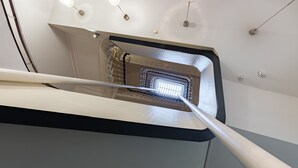 Una escala moderna amb tancament de vidre i tres llums penjants.