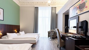 Habitació d'hotel amb dos llits, un escriptori, una cadira, una taula petita i una televisió.