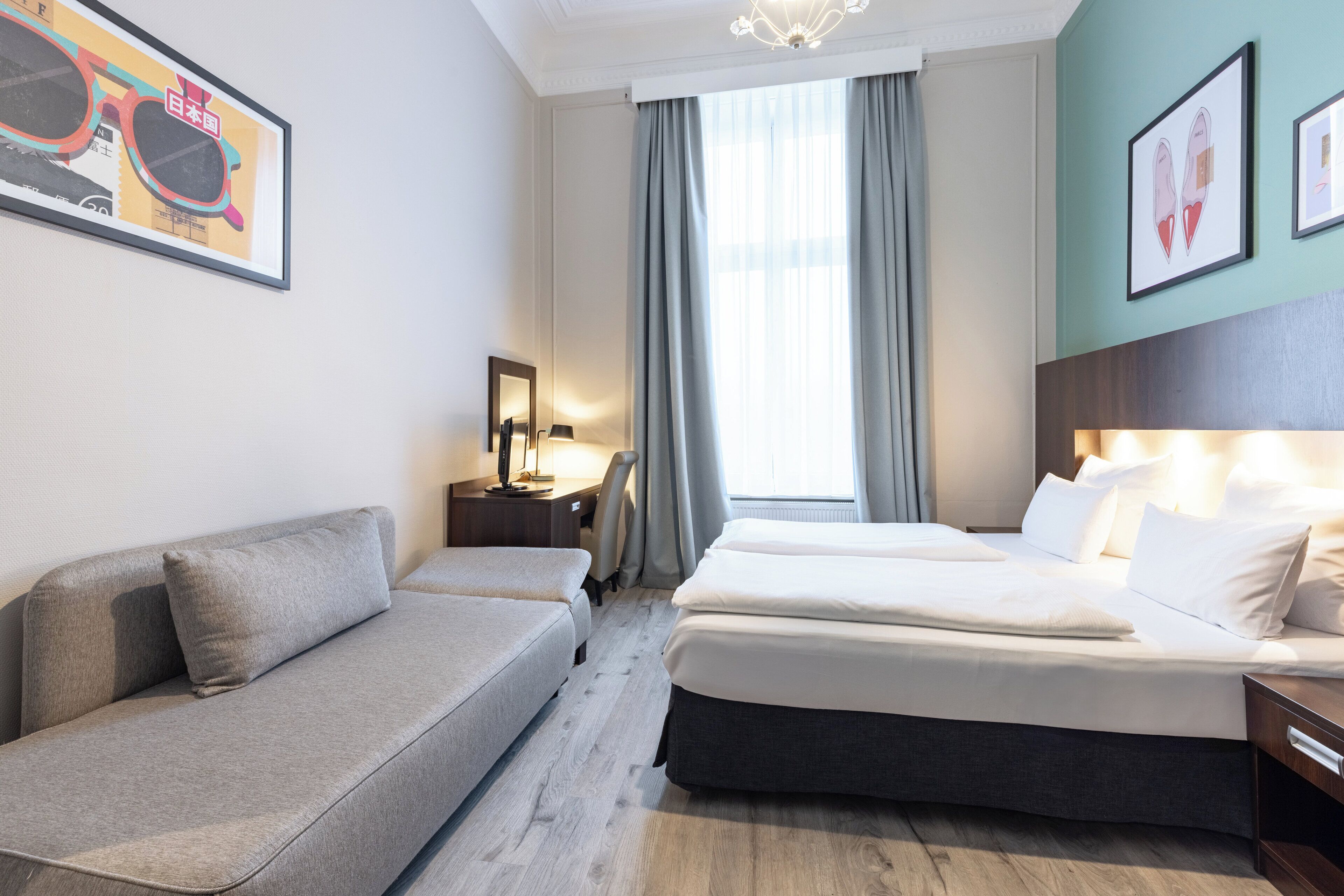 Ein Hotelzimmer mit Sofa, Bett, Schreibtisch und Stuhl.