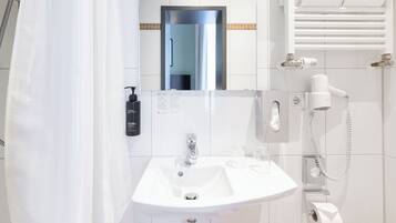 Un baño moderno con un lavabo blanco, un espejo, un perchero para toallas, un secador de pelo y un teléfono.