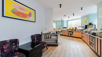 A modern cafe with a wooden counter, seating area, and a large framed artwork on the wall.