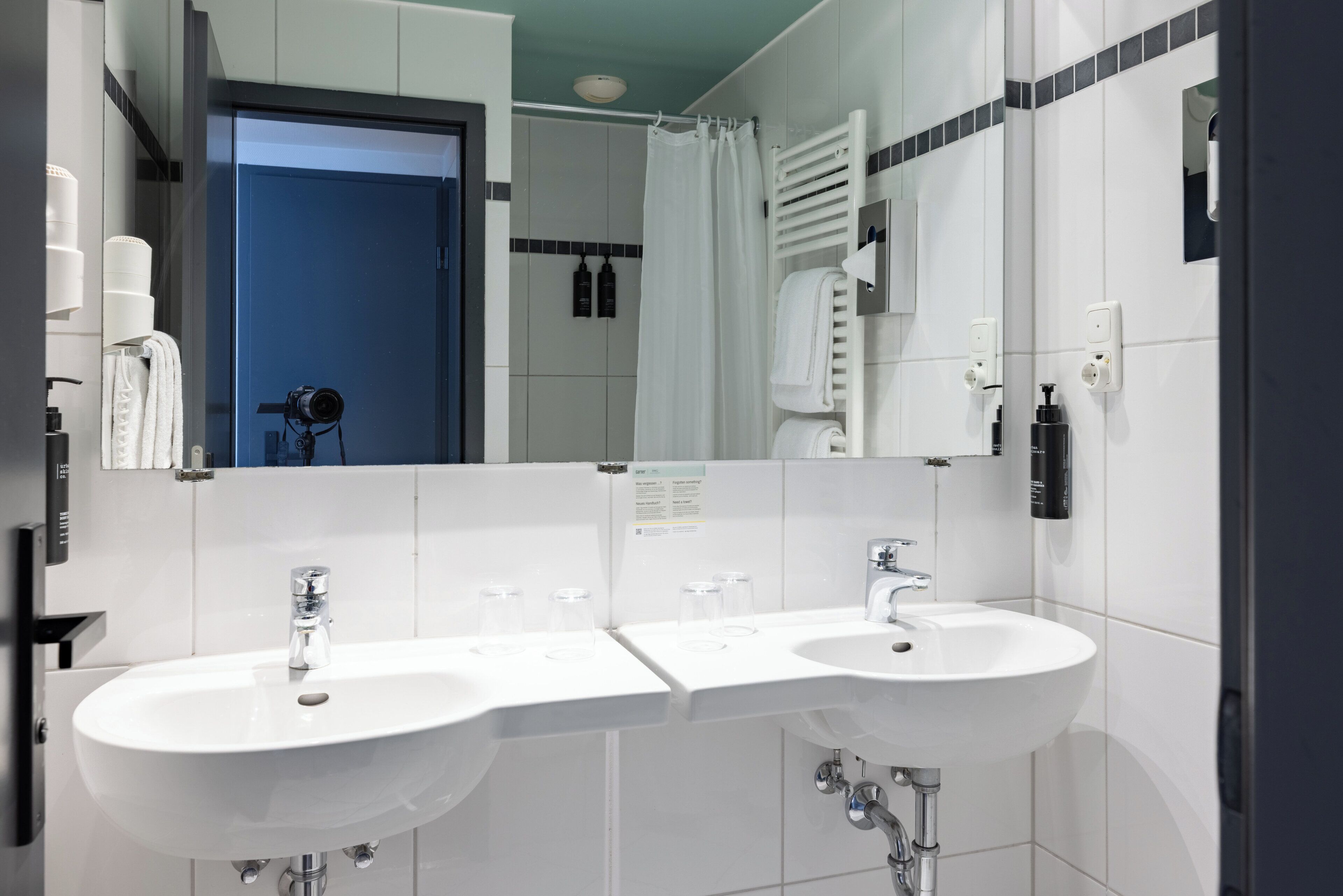 Un baño moderno con dos lavamanos, un espejo grande y una zona de ducha.