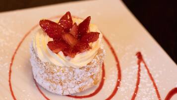 Un postre con crema batida y fresas sobre un pastel espolvoreado con azúcar glas.