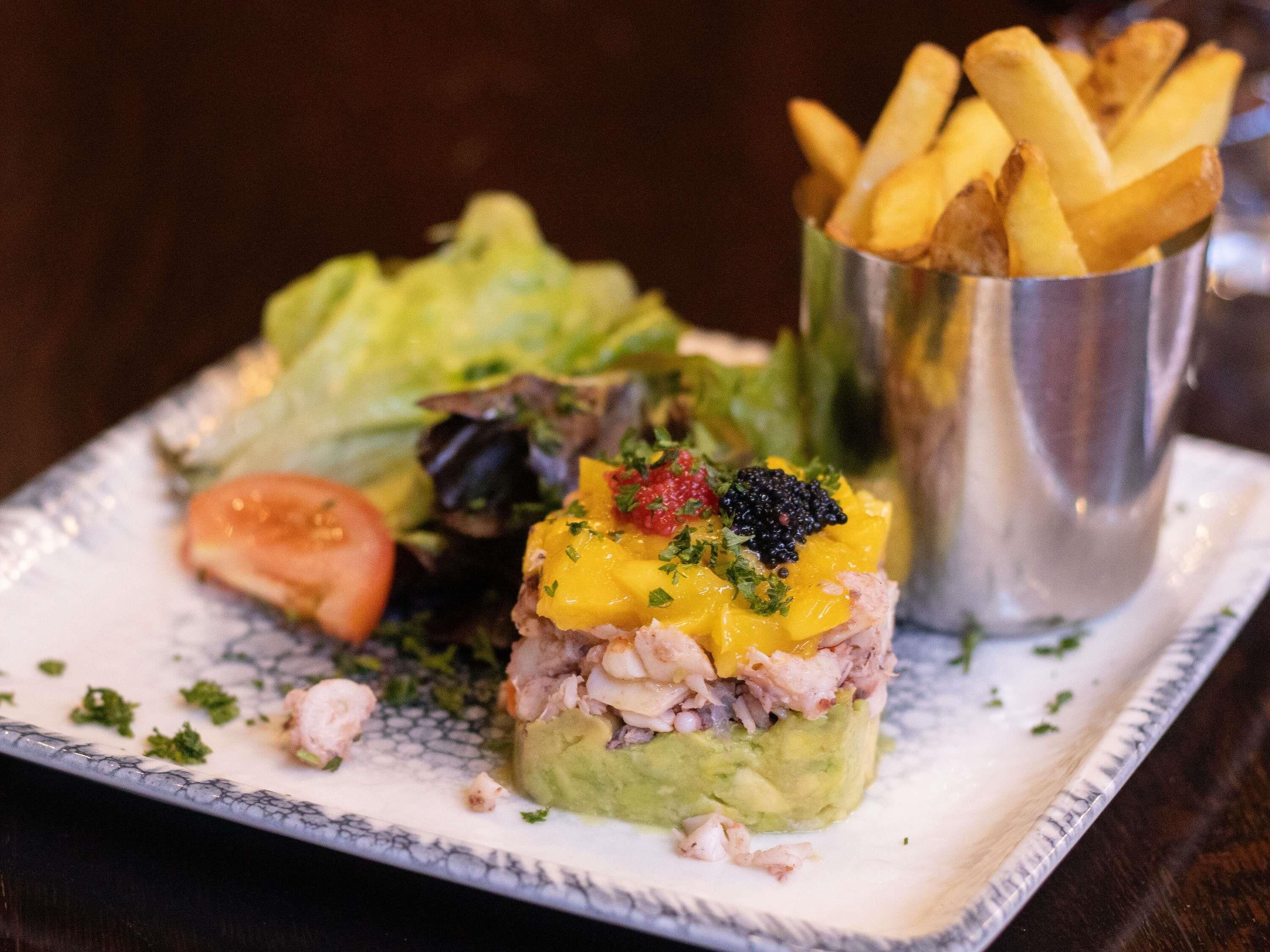 A plate with a layered dish, a side salad, and a cup of fries.