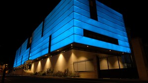 Un bâtiment moderne à la façade géométrique, illuminée de bleu la nuit.