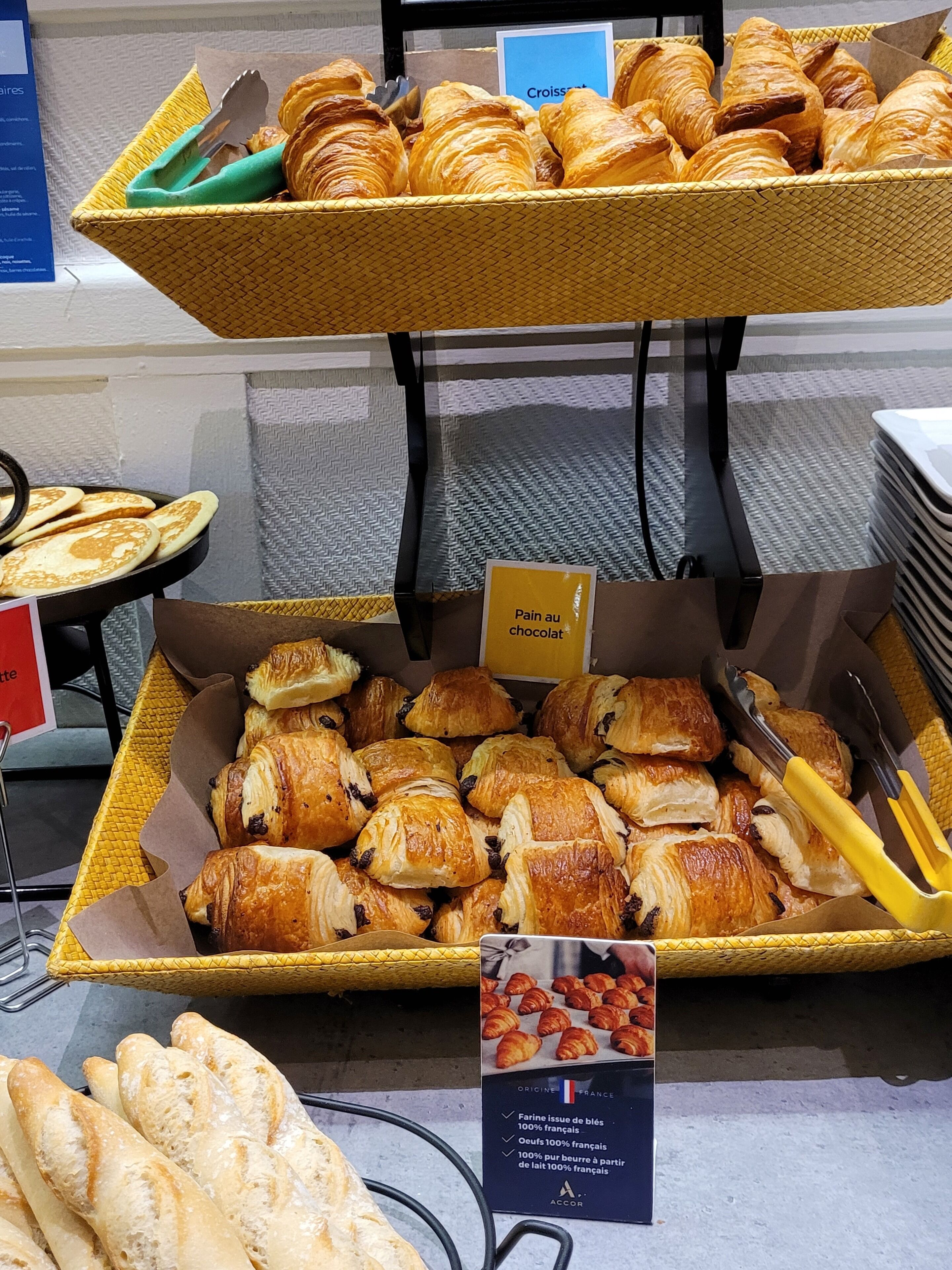 A display of various pastries including croissants and pain au chocolat, arranged on trays and in boxes.