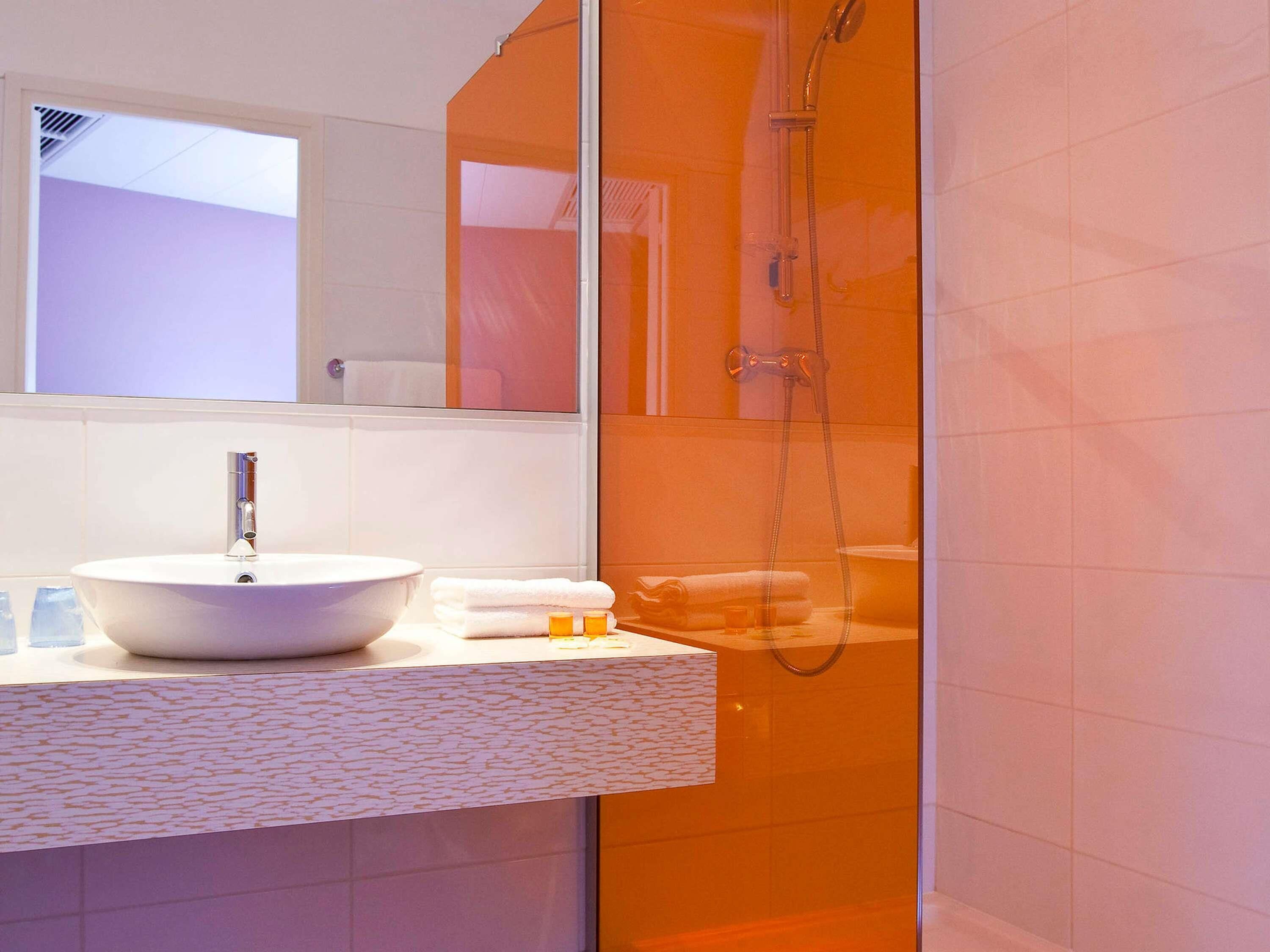 Ein Badezimmer mit Waschbecken, Spiegel und einer Duschkabine.