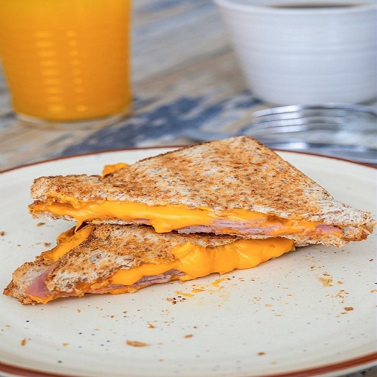 A grilled cheese sandwich with ham and melted cheese on a plate.