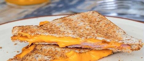 A grilled cheese sandwich with ham and melted cheese on a plate.