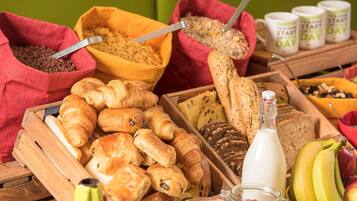 Ein reichhaltiges Frühstücksbuffet mit Gebäck, Brot, Früchten und Getränken.