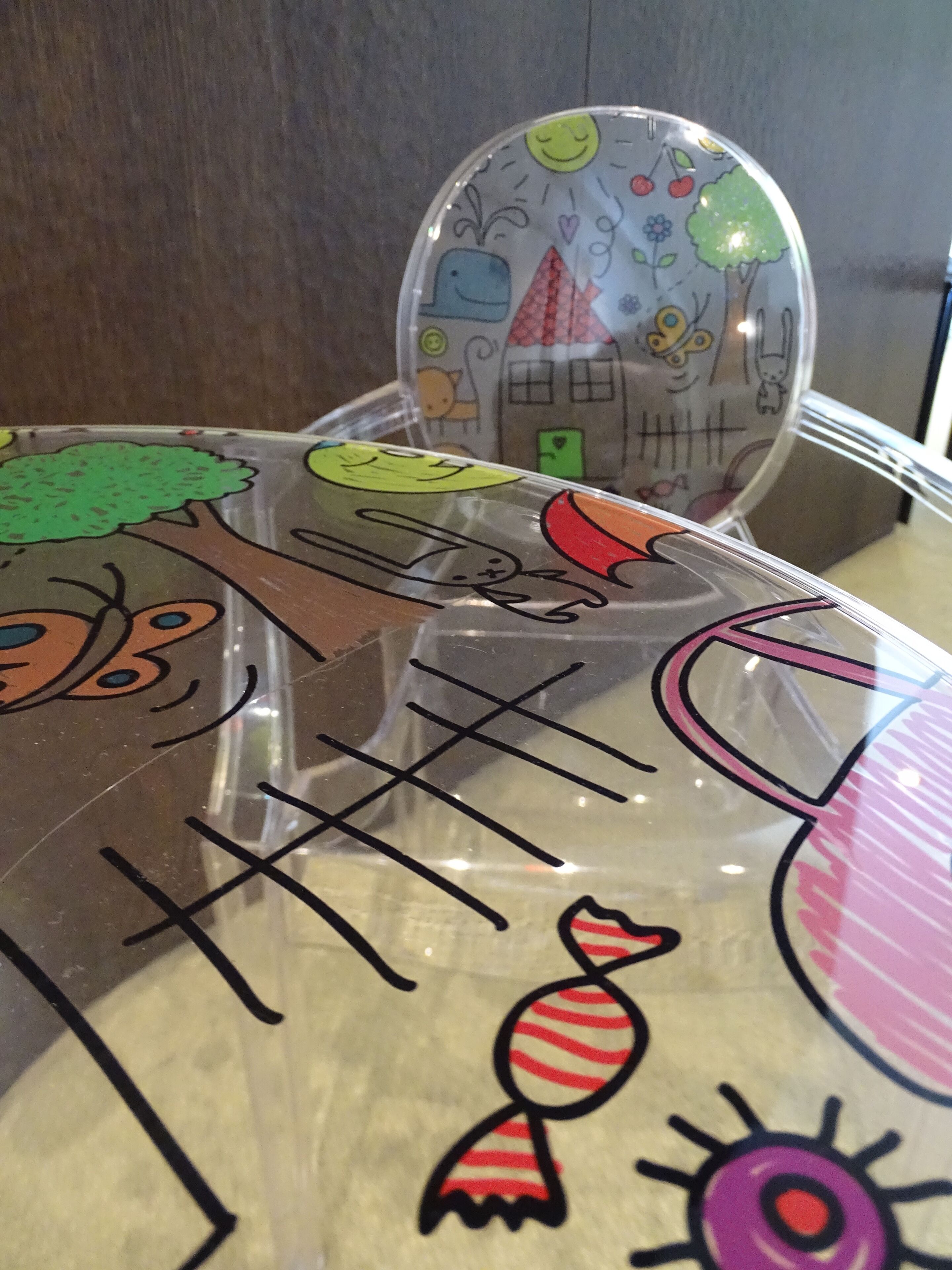 A transparent plastic bag with colorful drawings of a house, a tree, a sun, and a candy.