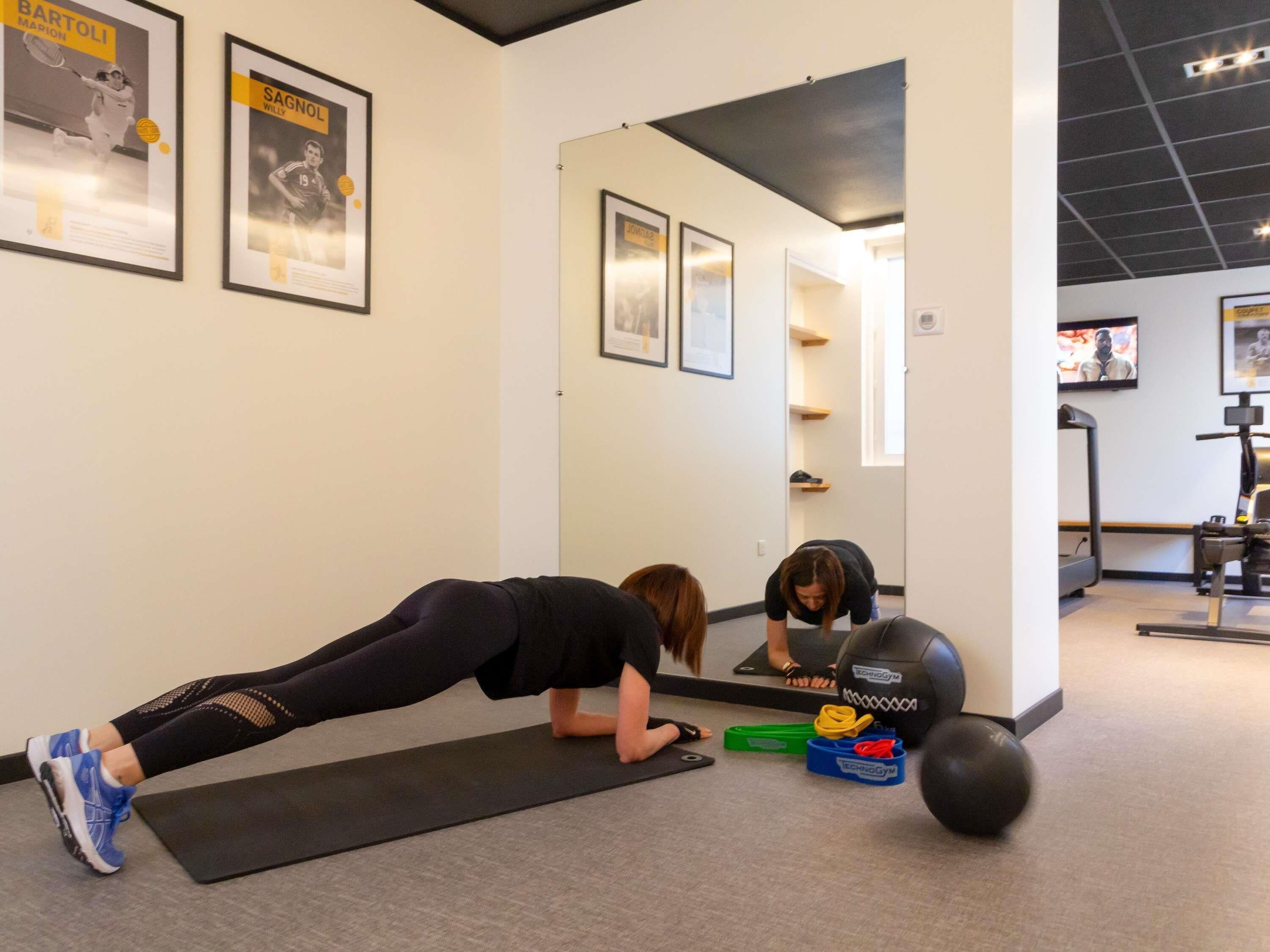 A gym with exercise equipment, a black mat, and posters on the wall.