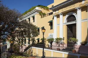 A yellow building with "EL CONVENTO" sign, columns, and a staircase leading to the entrance. - Hotel El Convento (San Juan)