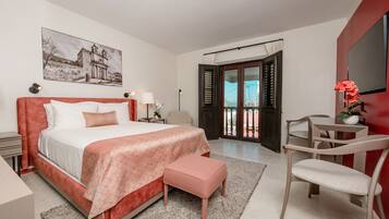 A bedroom with a bed, bedside tables, a chair, a desk, and a balcony with a view.