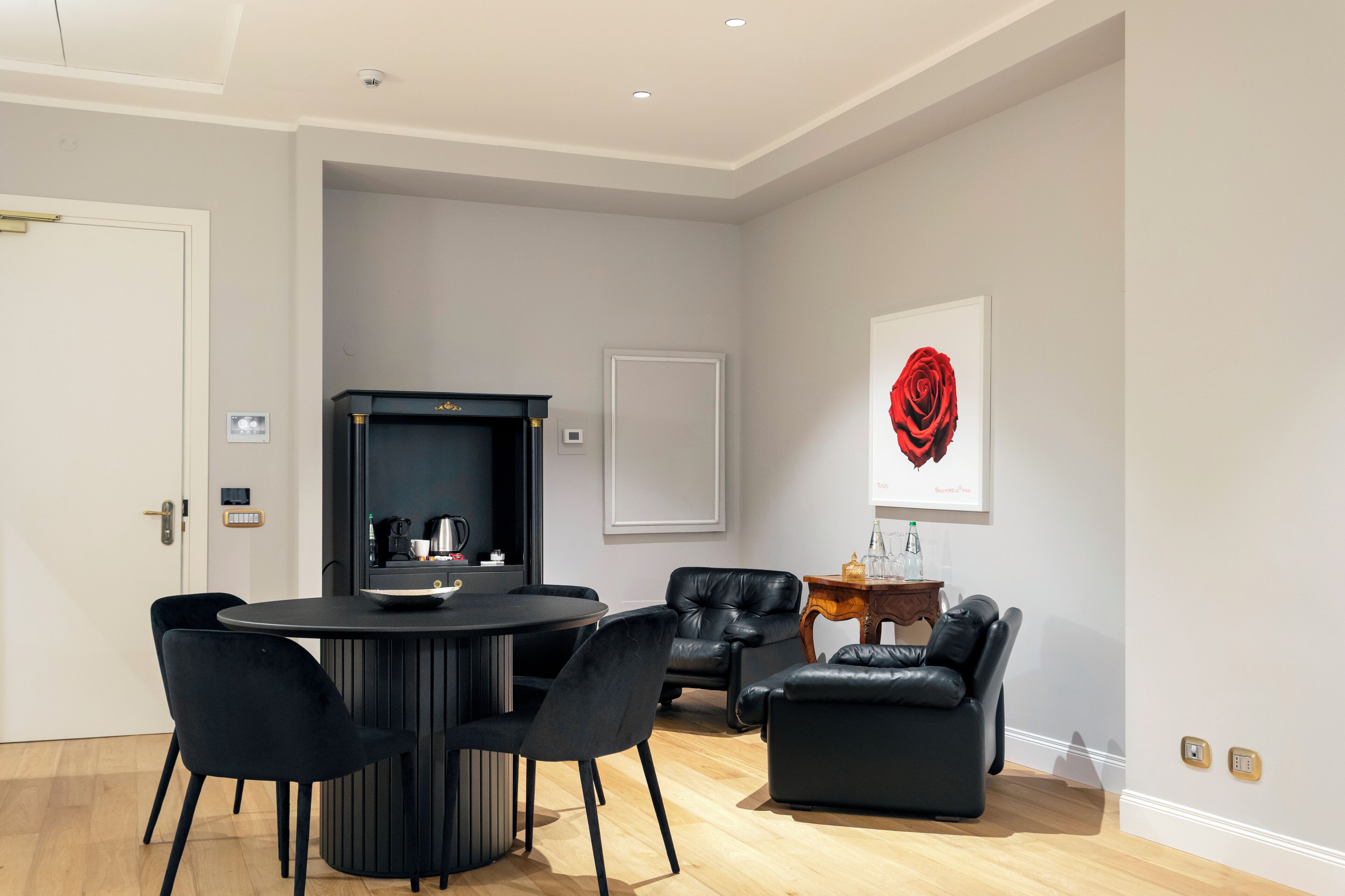 A modern living room with a round black table, black chairs, a black leather sofa, and a fireplace.