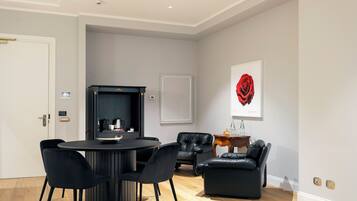A modern living room with a round black table, black chairs, a black leather sofa, and a fireplace.