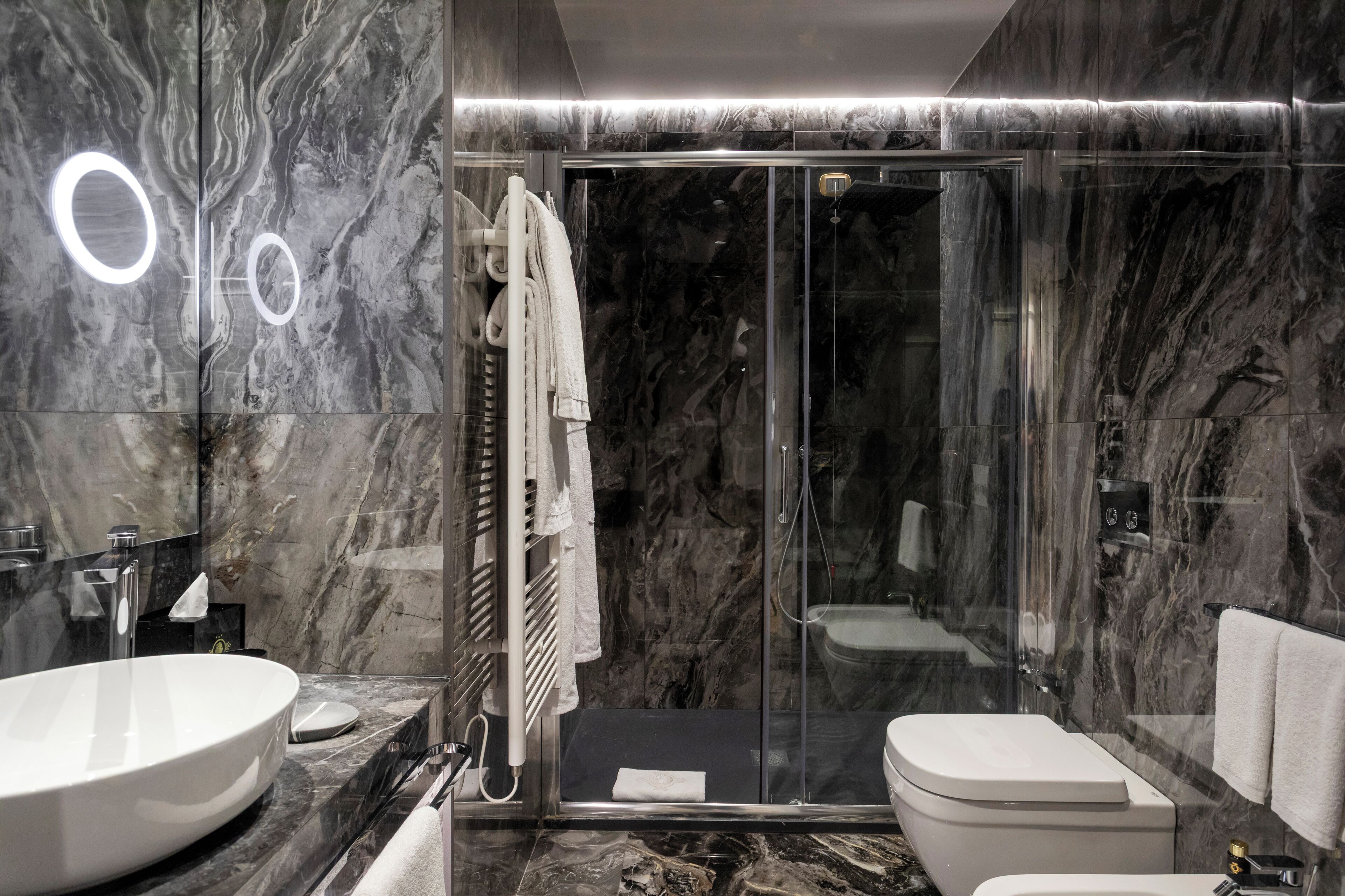 Ein modernes Badezimmer mit einem großen, ovalen Waschbecken, einer Duschkabine aus Glas und einer Toilette.