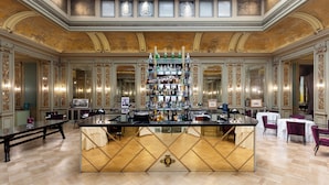 A luxurious bar area with a central bar, multiple shelves of bottles, and elegant seating arrangements. - Grand Hotel et Des Palmes (Palermo)