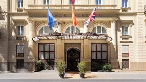 A grand hotel facade with classical architecture, featuring a prominent entrance, flags, and a sign reading "GRAND HOTEL DES PALMIERS". - Grand Hotel et Des Palmes (Palermo)
