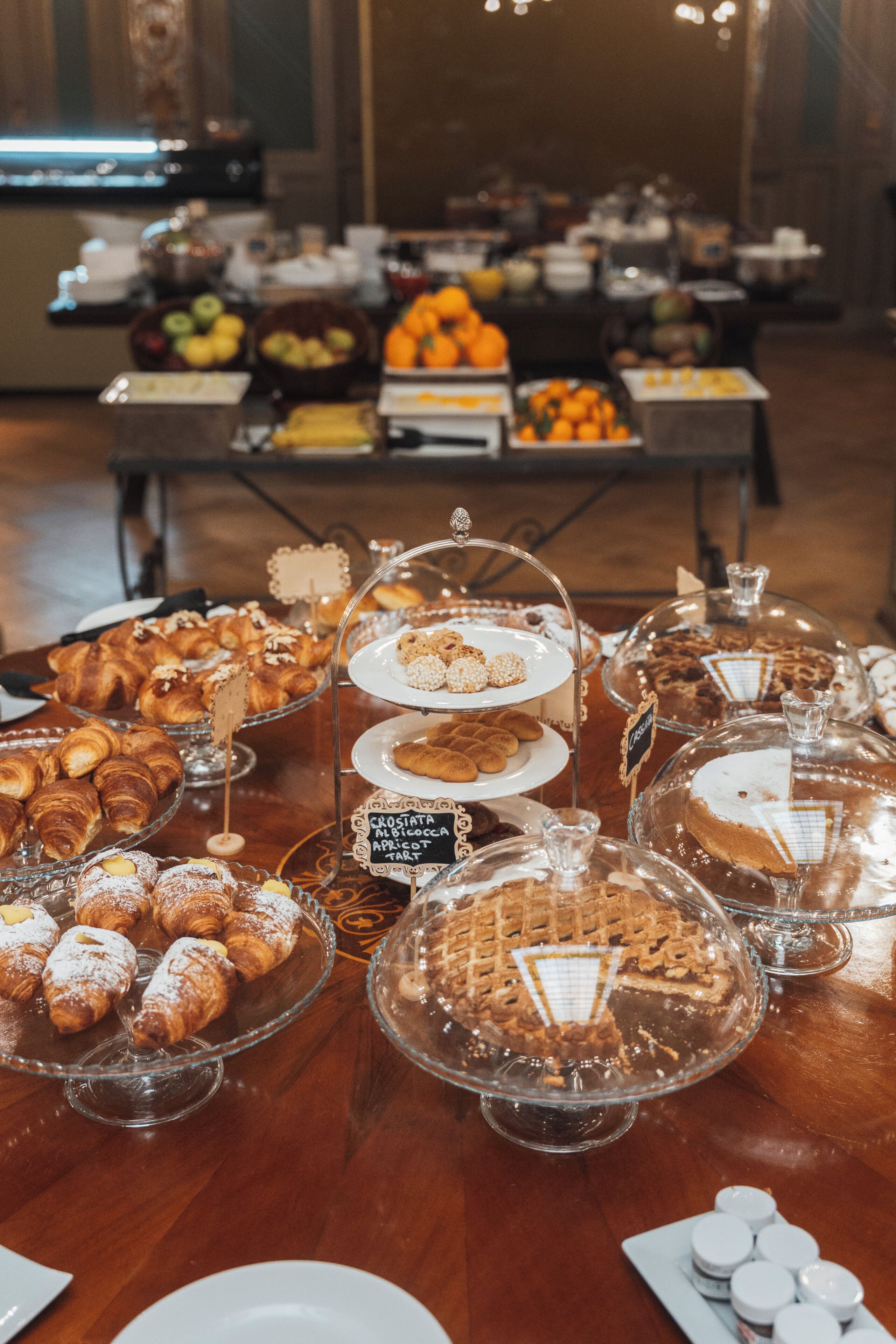 A buffet with various pastries and desserts displayed on glass stands.