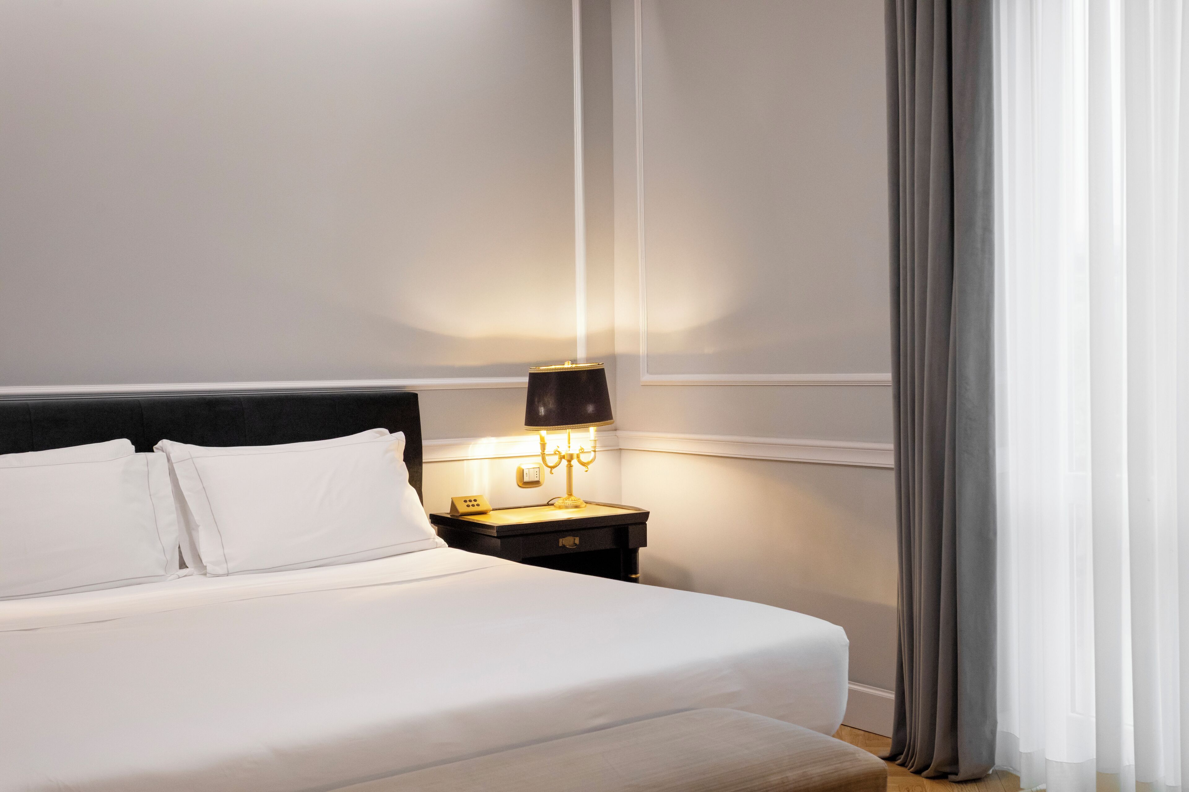 A neatly made bed with white linens in a hotel room.