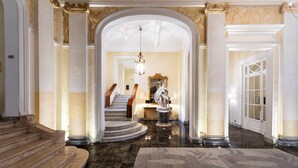 A grand hallway with marble floors, a grand staircase, and classical columns. - Grand Hotel et Des Palmes (Palermo)