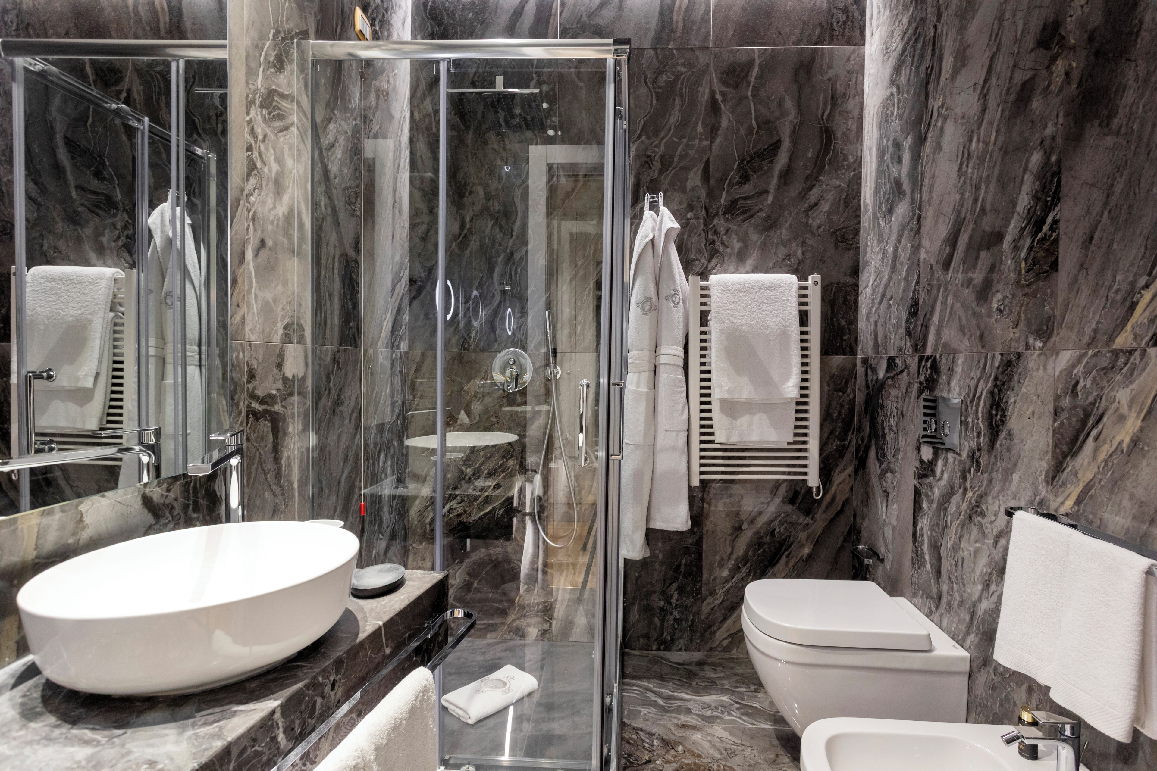 A modern bathroom with a glass-enclosed shower, a large oval sink, and a toilet.