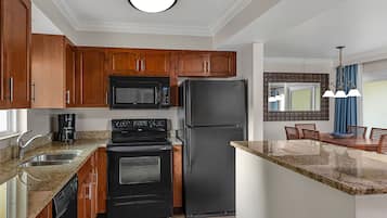 Une cuisine moderne avec des meubles en bois, un réfrigérateur noir, un four à micro-ondes, une cuisinière et un lave-vaisselle.