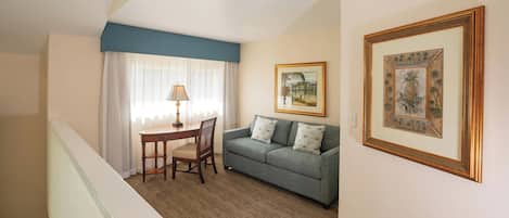 A room with a sofa, a table, and two framed pictures on the wall.