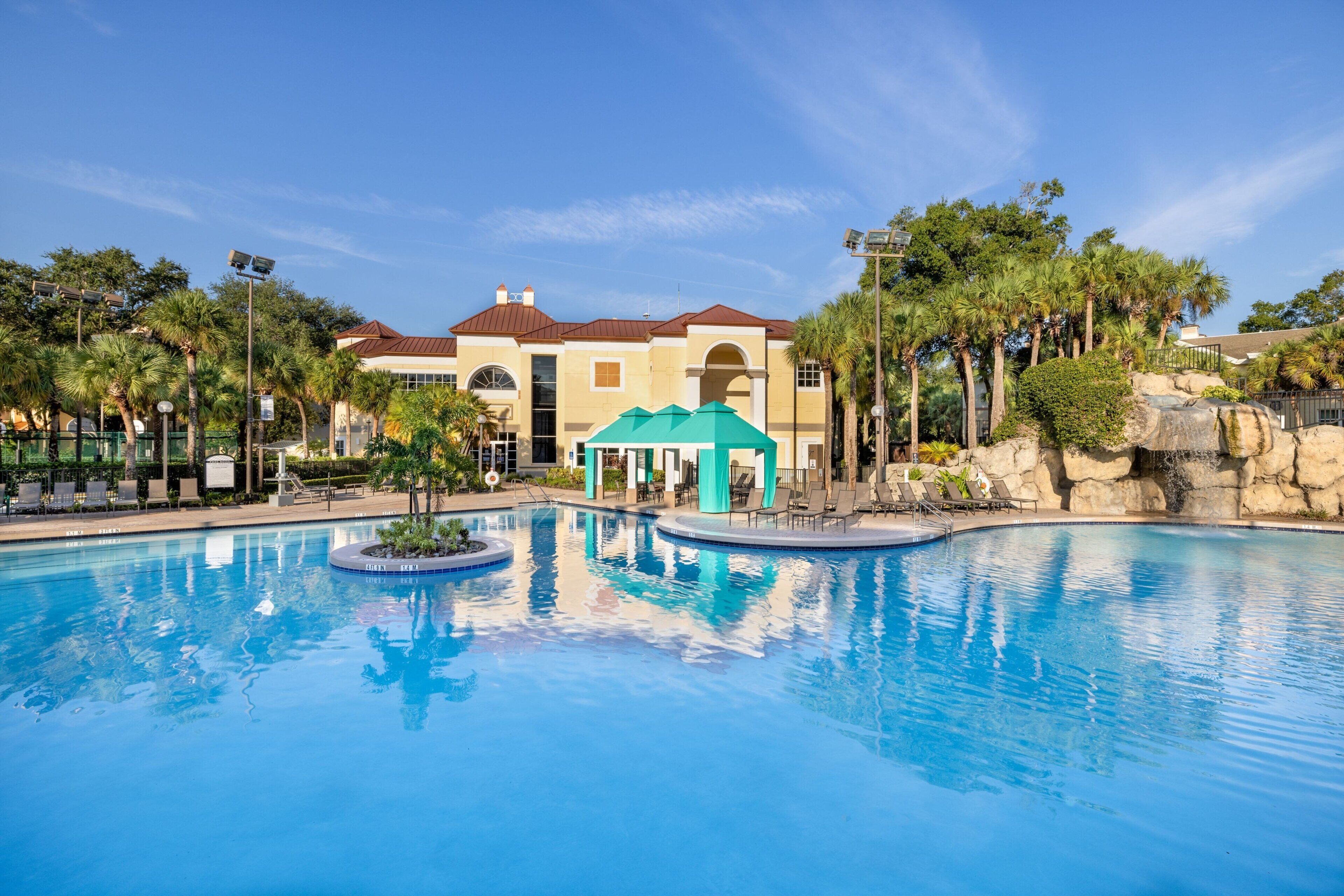 A swimming pool with lounge chairs and a building with a green roof in the background.
