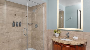 A modern bathroom with a glass-enclosed shower, a sink with a granite countertop, and a wooden vanity.