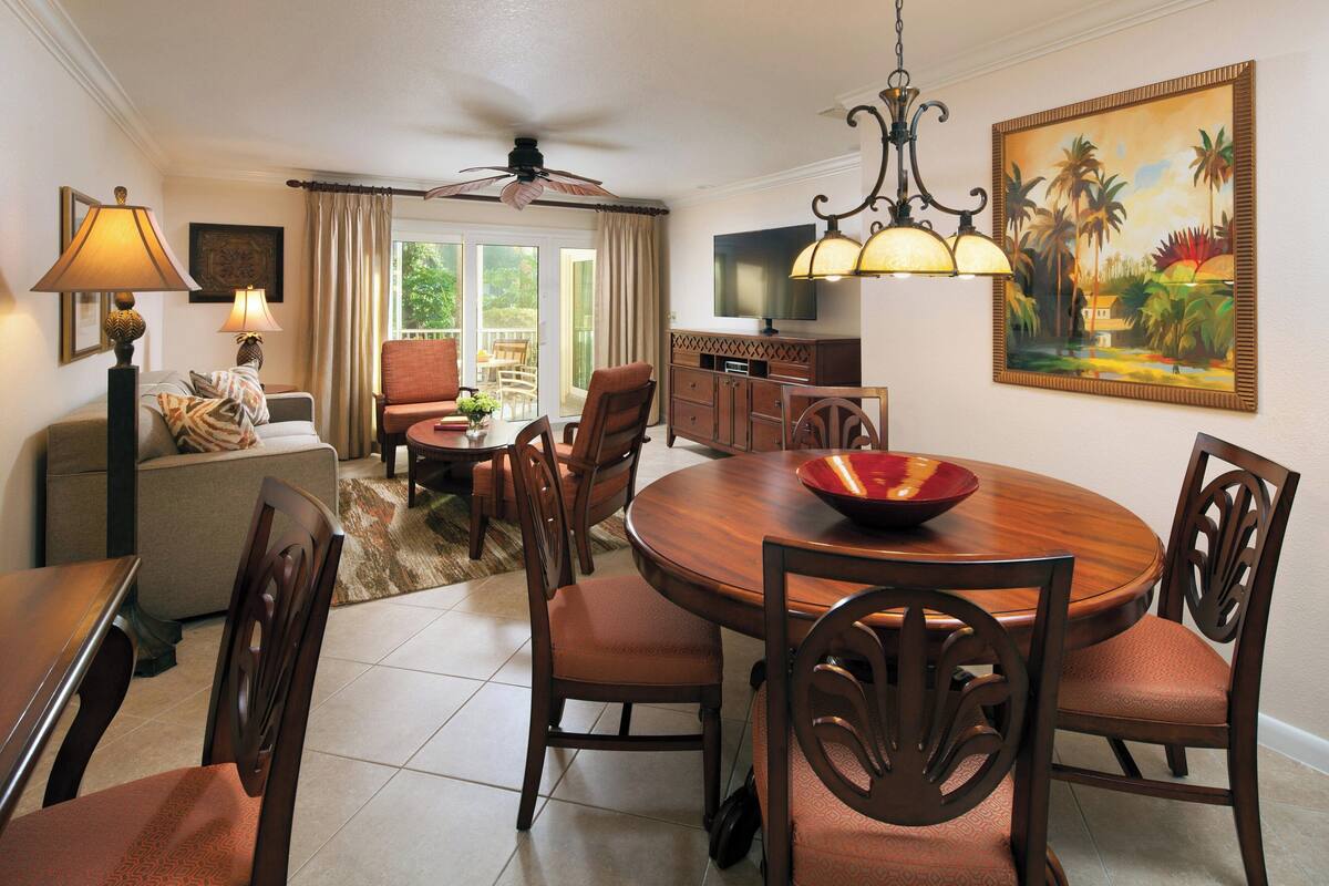 A dining area with a round table, chairs, and a television in the background.