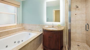 Une salle de bain avec une baignoire, un meuble-lavabo avec un miroir et un espace douche.