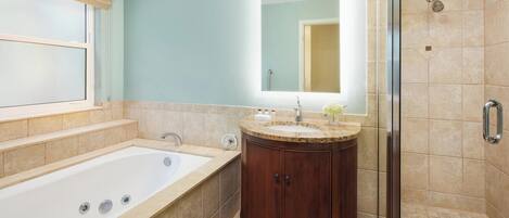 A bathroom with a bathtub, a vanity with a mirror, and a shower area.