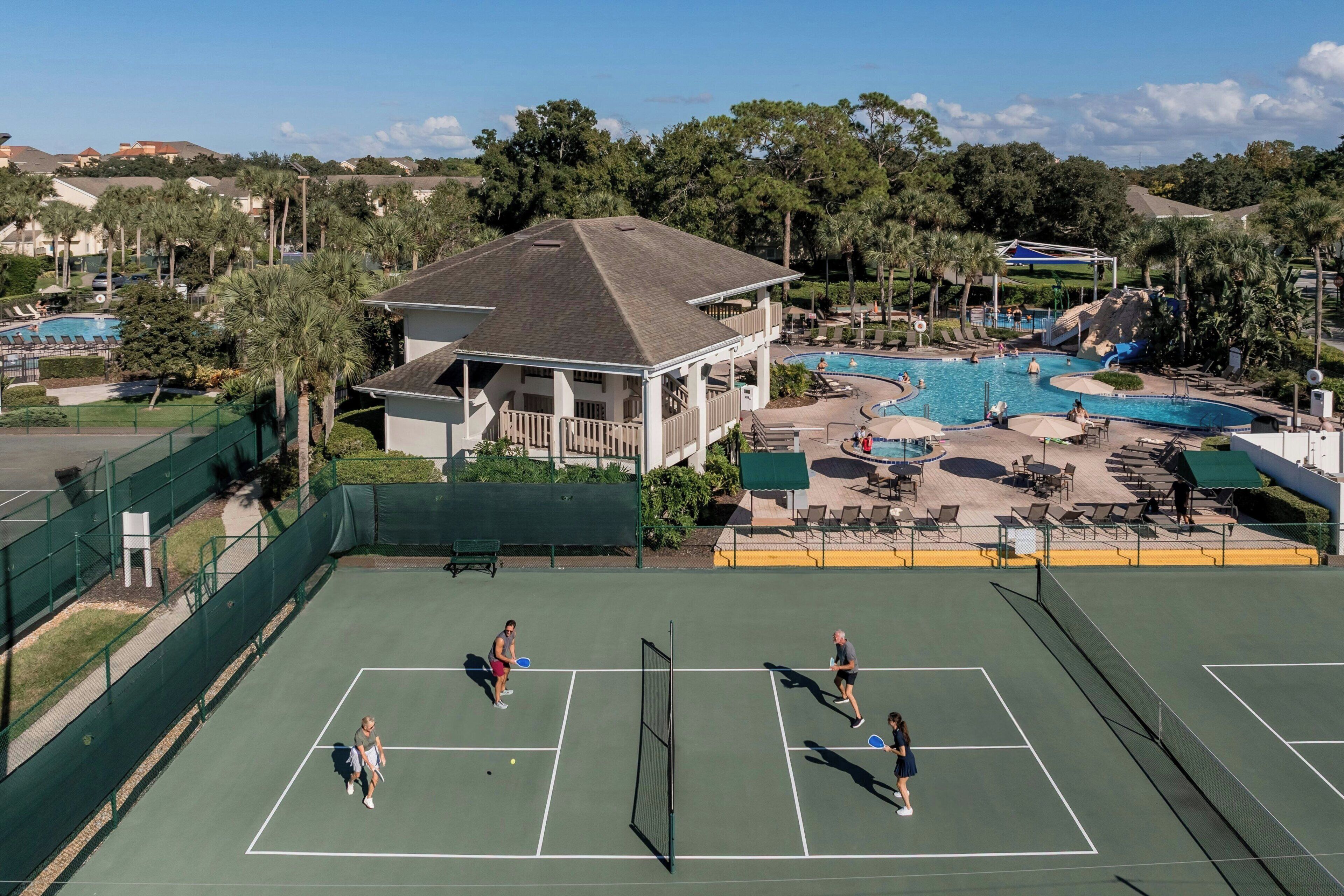 A tennis court with a pool and water slide nearby.