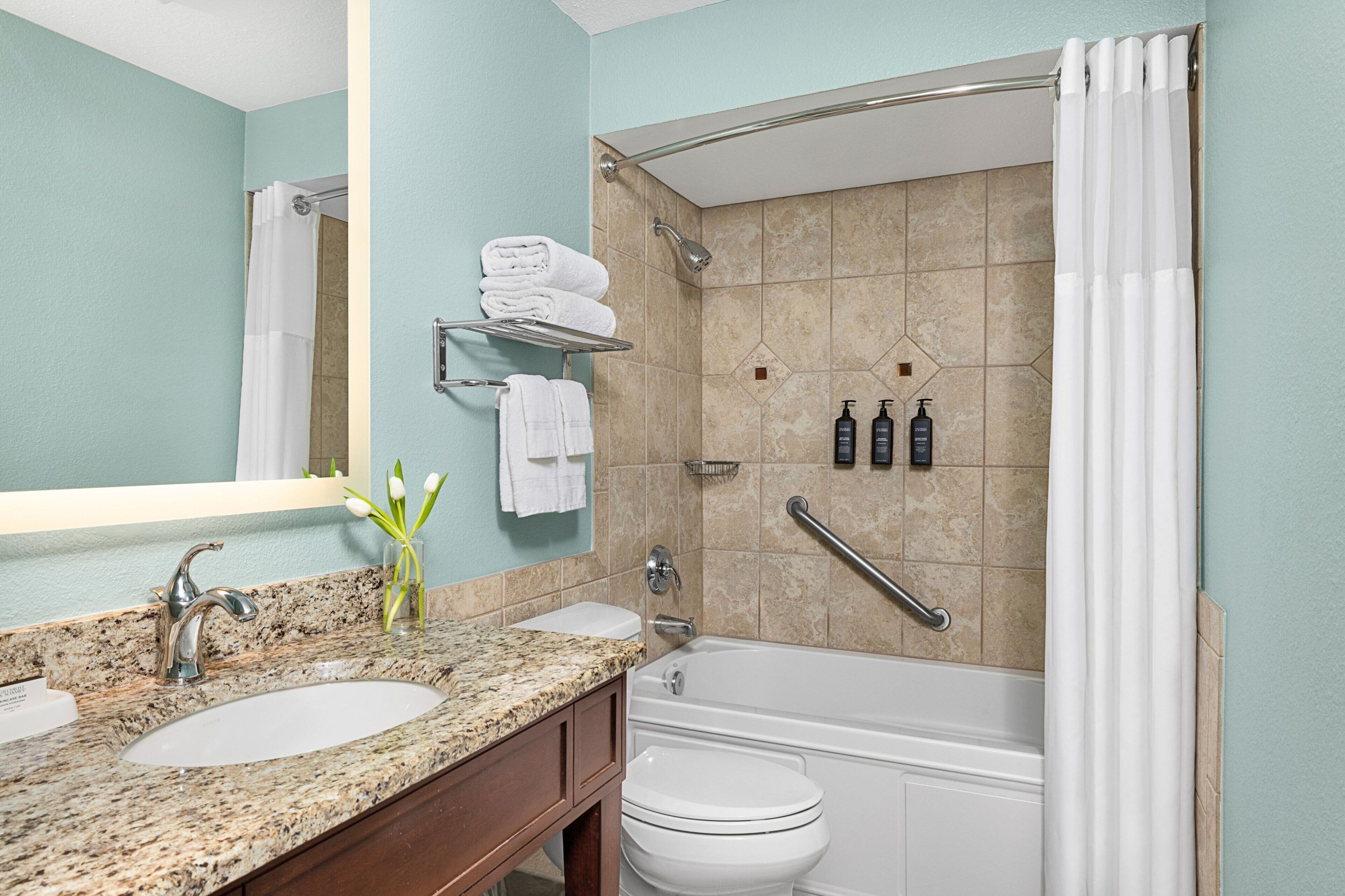A bathroom with two sinks, a toilet, a bathtub, and a shower with a grab bar.