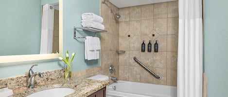 A bathroom with two sinks, a toilet, a bathtub, and a shower with a grab bar.