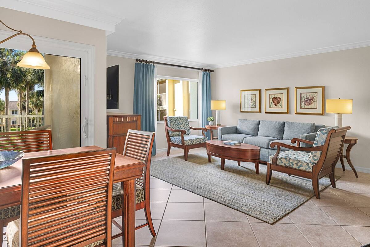 A living room with a dining area, featuring wooden furniture, a sofa, and a coffee table.