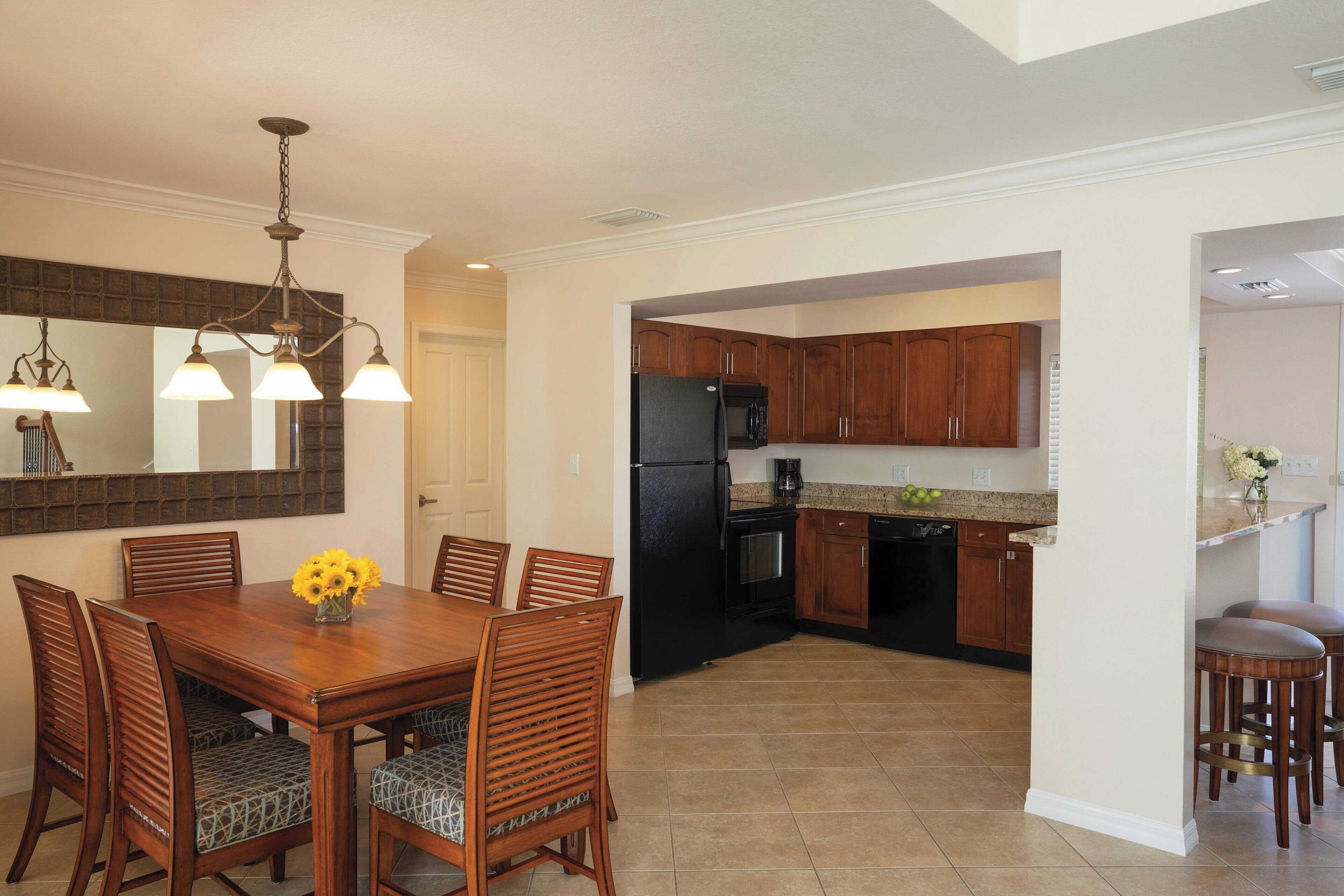 A spacious kitchen with wooden cabinets, a black refrigerator, and a dining area with a wooden table and chairs.