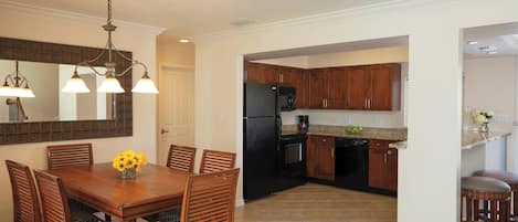 A spacious kitchen with wooden cabinets, a black refrigerator, and a dining area with a wooden table and chairs.