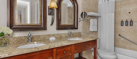 A bathroom with two sinks, a toilet, a shower, and a mirror.