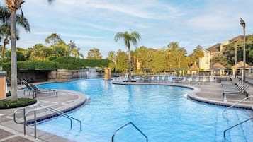 A swimming pool with multiple lanes, lounge chairs, and palm trees.