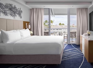 Una habitación de hotel con una cama grande, un escritorio, una silla y vistas al exterior.