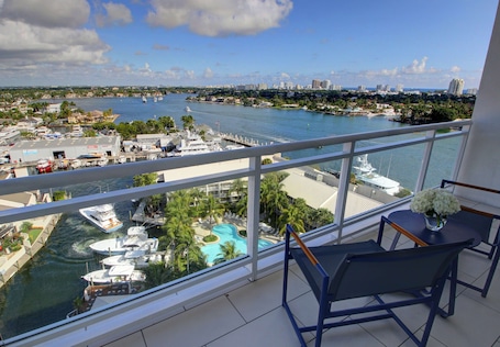 A balcony with a view of a marina, a pool, and a cityscape.