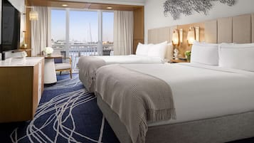 Une chambre d’hôtel avec un grand lit, un bureau, une chaise, une télévision et une vue sur la ville.