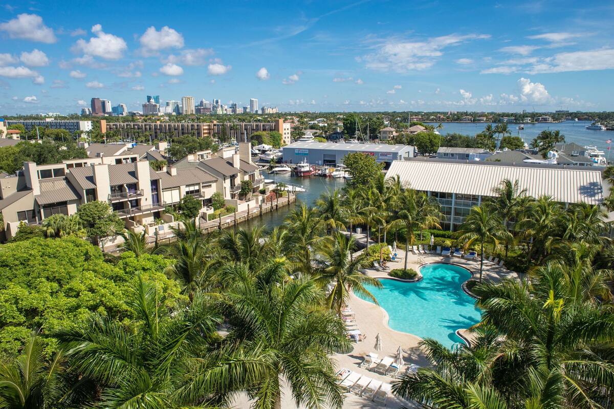 A resort with a swimming pool, palm trees, and a marina.
