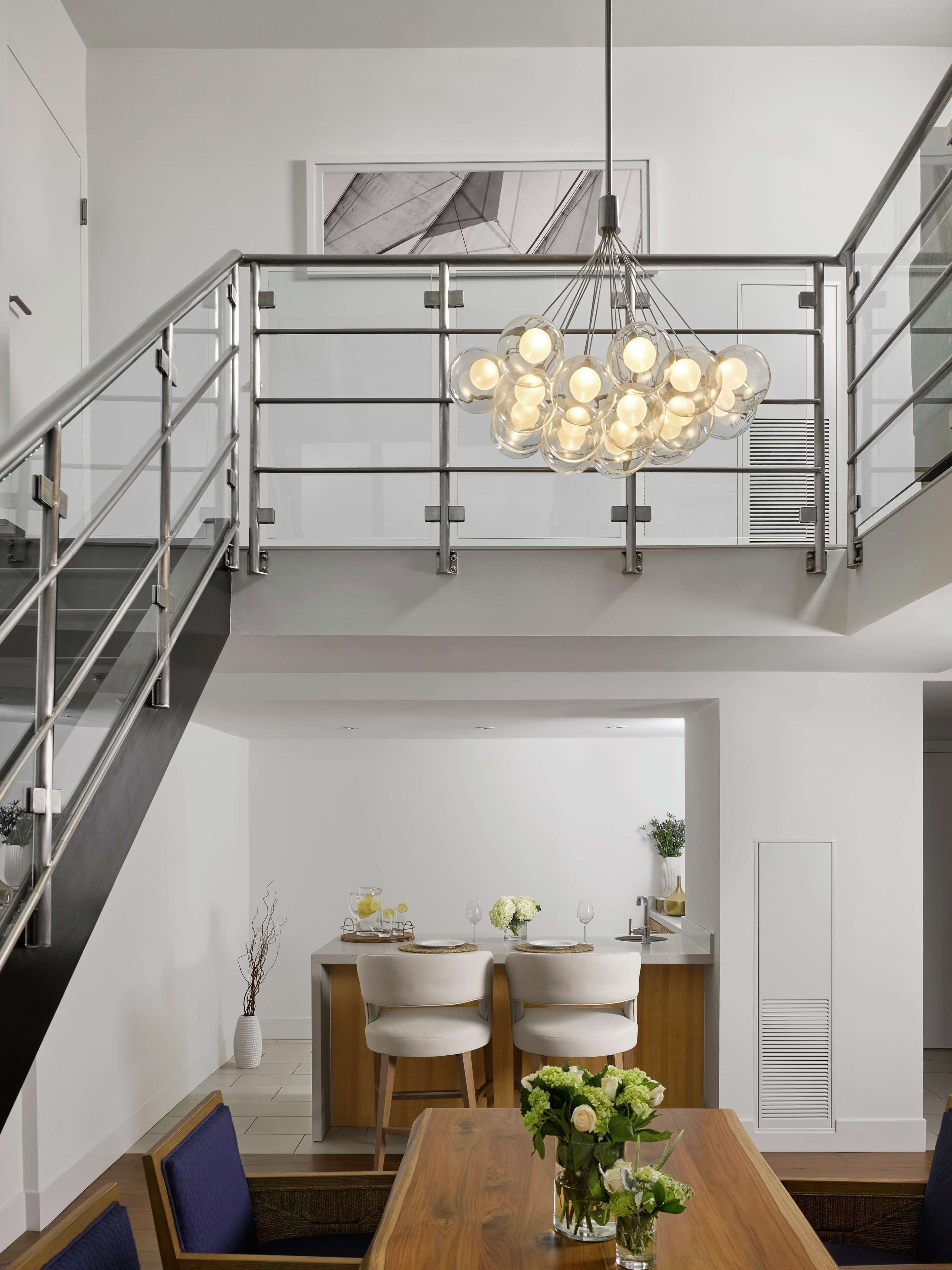 A modern interior with a staircase, dining area, and a chandelier.